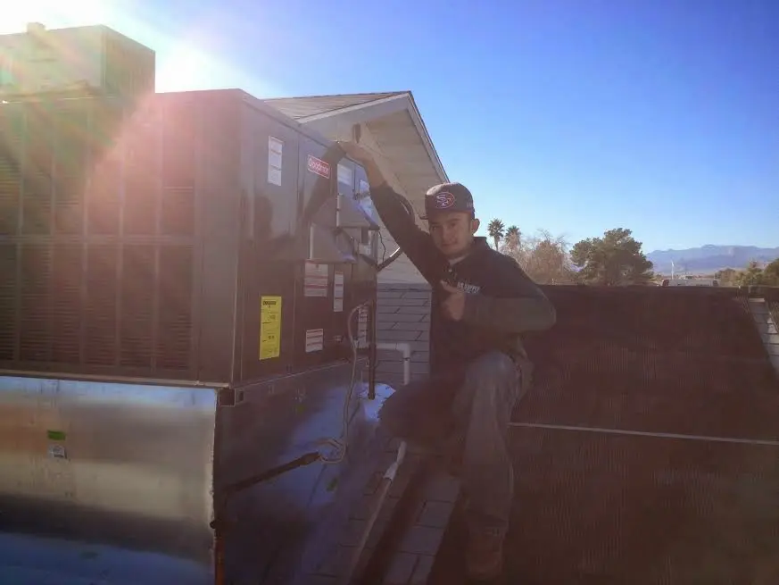 HVAC technician performing Air Duct Cleaning on a rooftop unit in Upper Milford
